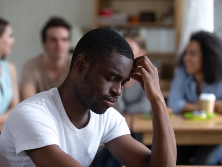 En mann som sitter ved et bord foran en gruppe mennesker.